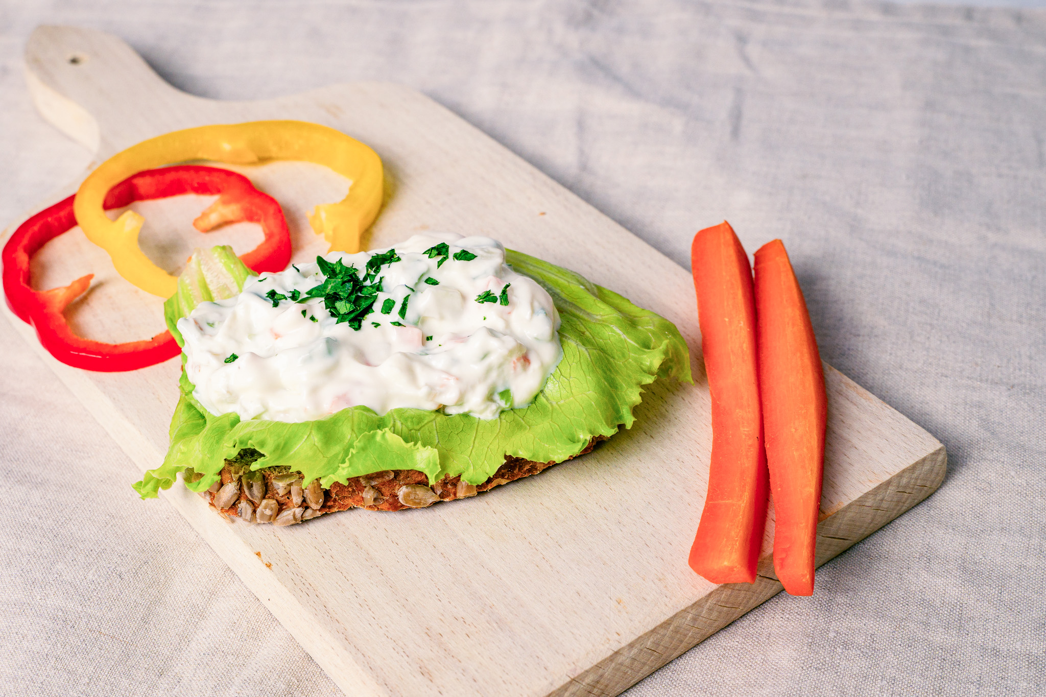 Abbildung Rohkost-Power-Brötchen auf Schneidbrett mit Karotten und Paprika