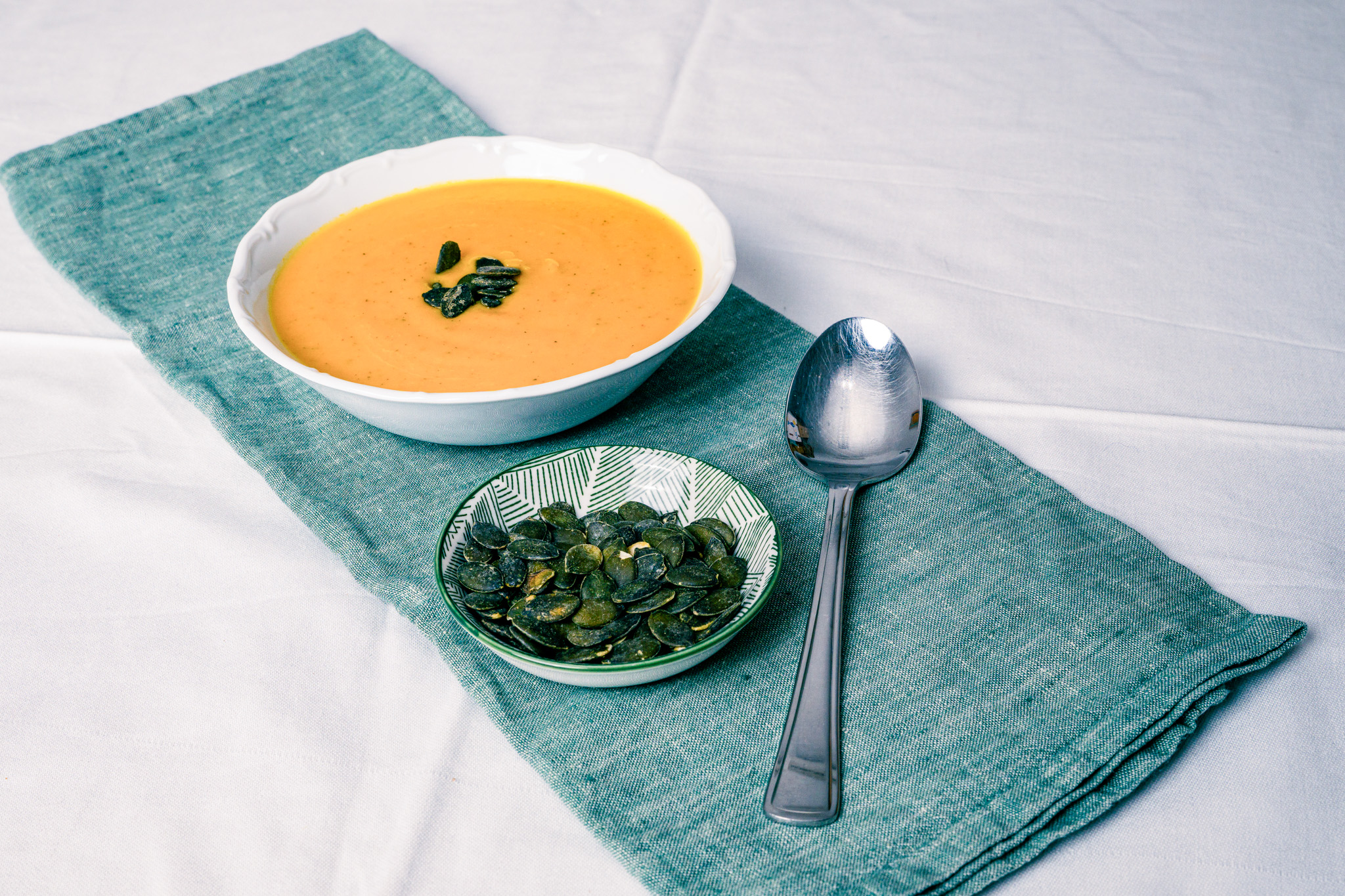 Abbildung von Kürbiscremesuppe im Teller mit Kürbiskernen und Löffel
