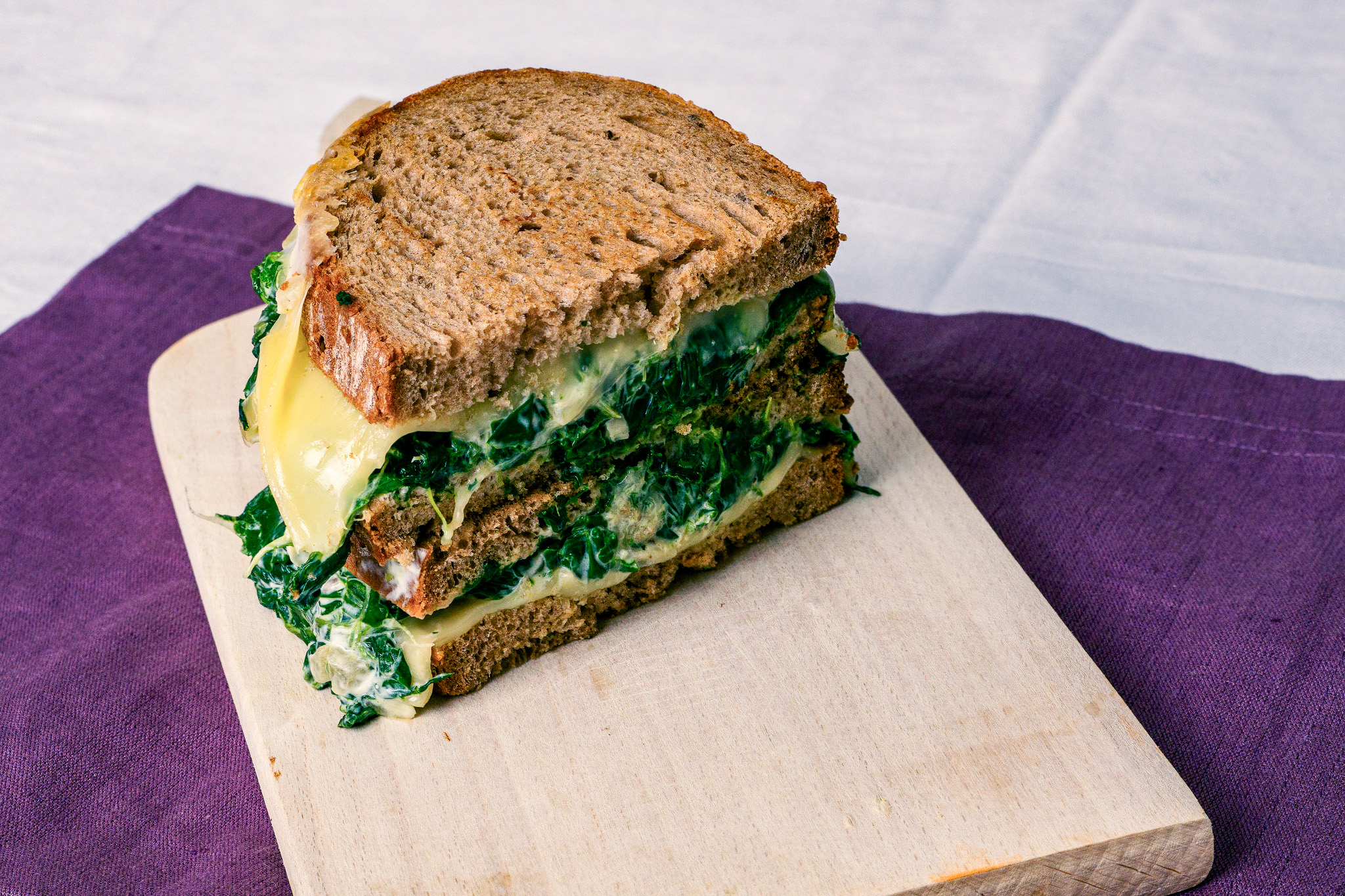 Abbildung von Schwarzbrottoast mit Spinat auf Schneidbrett