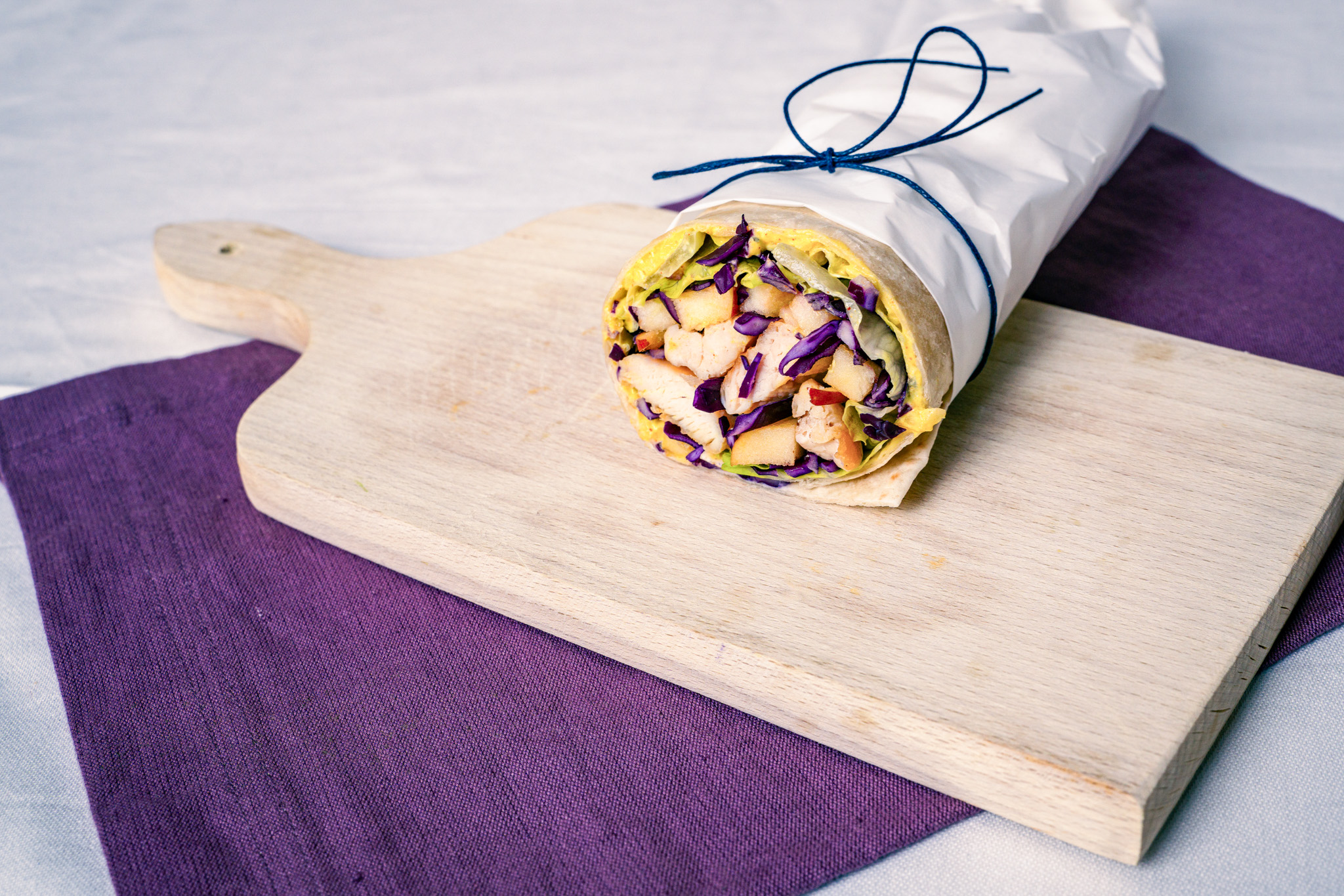 Abbildung von Hühner-Apfel-Curry-Wrap auf Schneidbrett