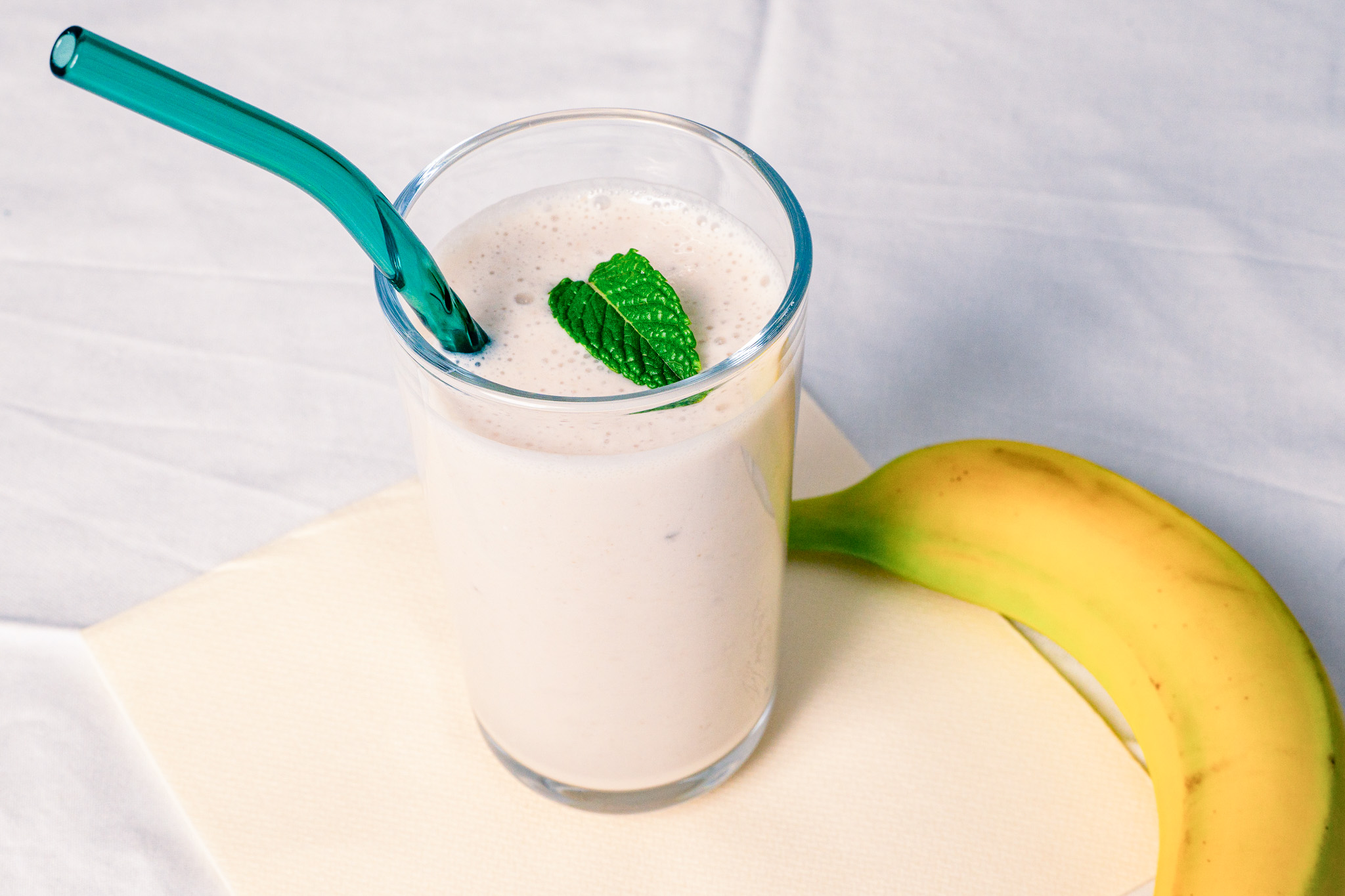 Abbildung von Bananen-Lassi im Glas mit einer Banane