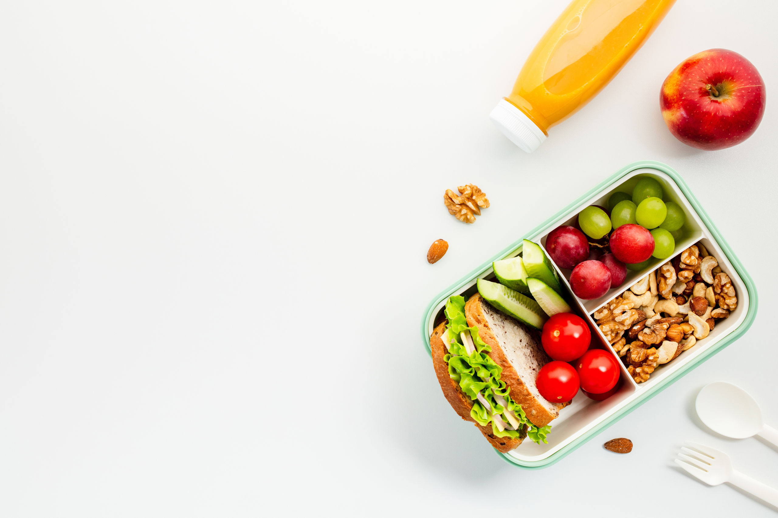 Eine Jausenbox mit einem belegten Brot, Gemüse und Nüssen