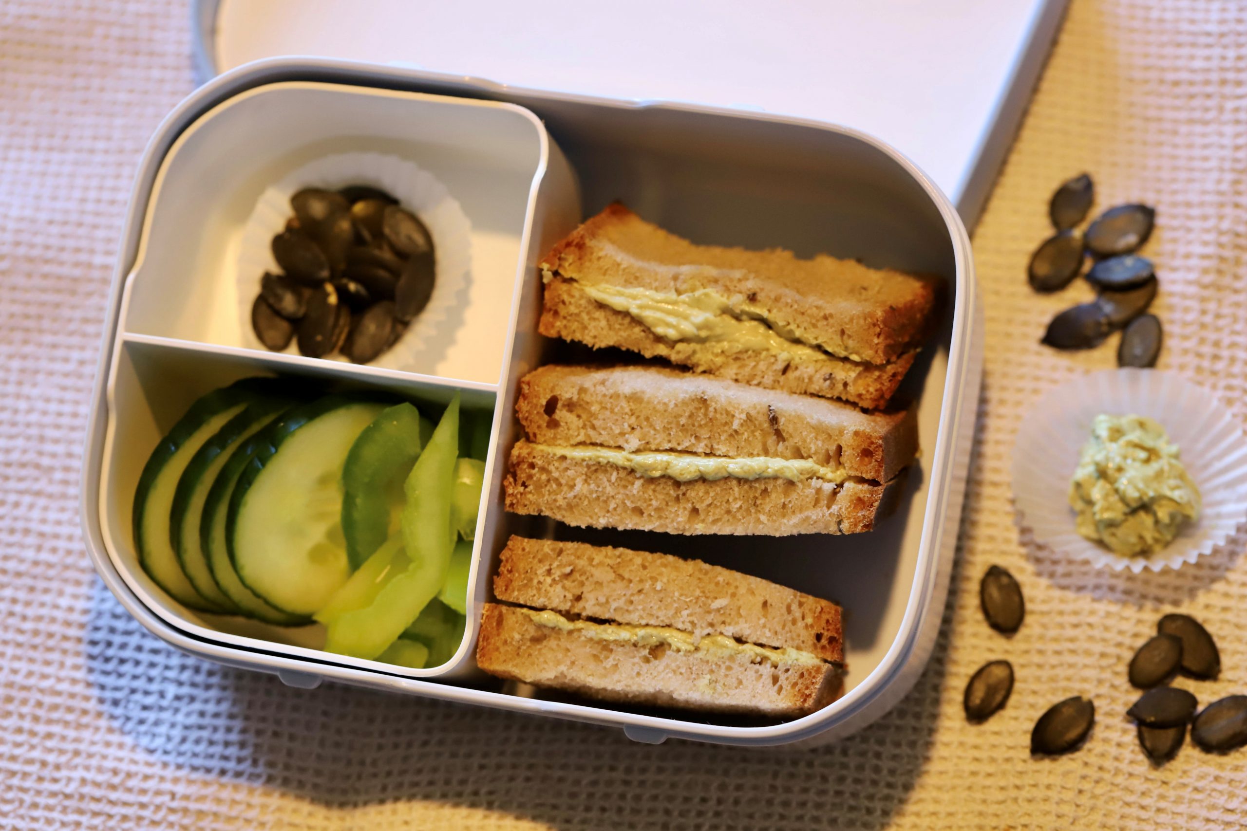 Herbstliche Jausenbox mit Aufstrichbroten, Gurke, Paprika, Kürbiskernen und herbstlicher Deko